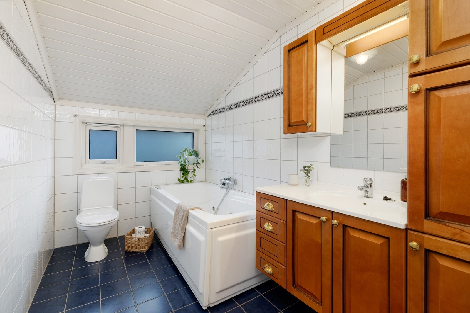 Baderommet i etasjen er flislagt med toalett, badekar og servant samt oppbevaring. Galleribilde