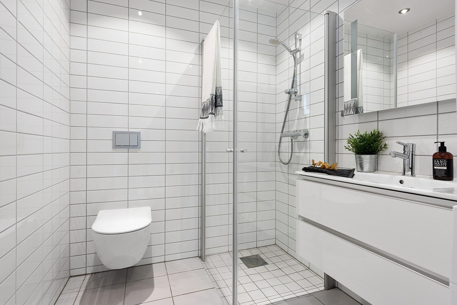 Badet er innredet med vegghengt toalett og dusjhjørne med glassdører Galleribilde