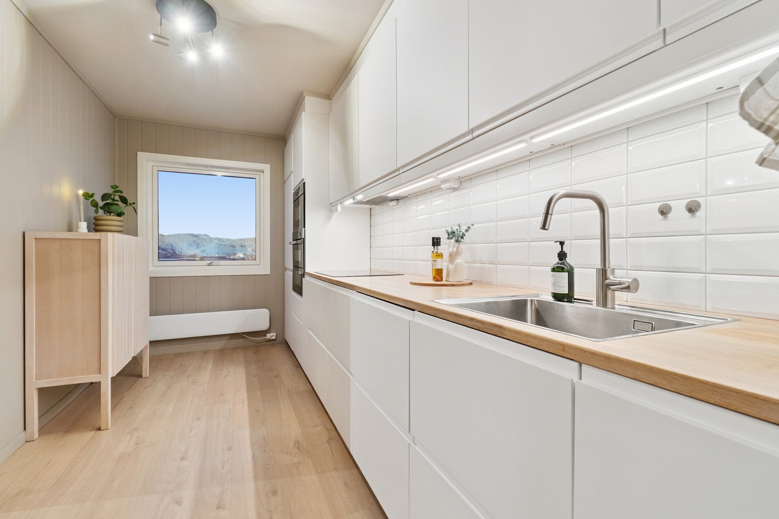 Kjøkkenet ble oppgradert i 2019, og fremstår svært moderne og tidløst med slette hvite fronter og en benkeplate som harmonerer fint med gulvet. Galleribilde