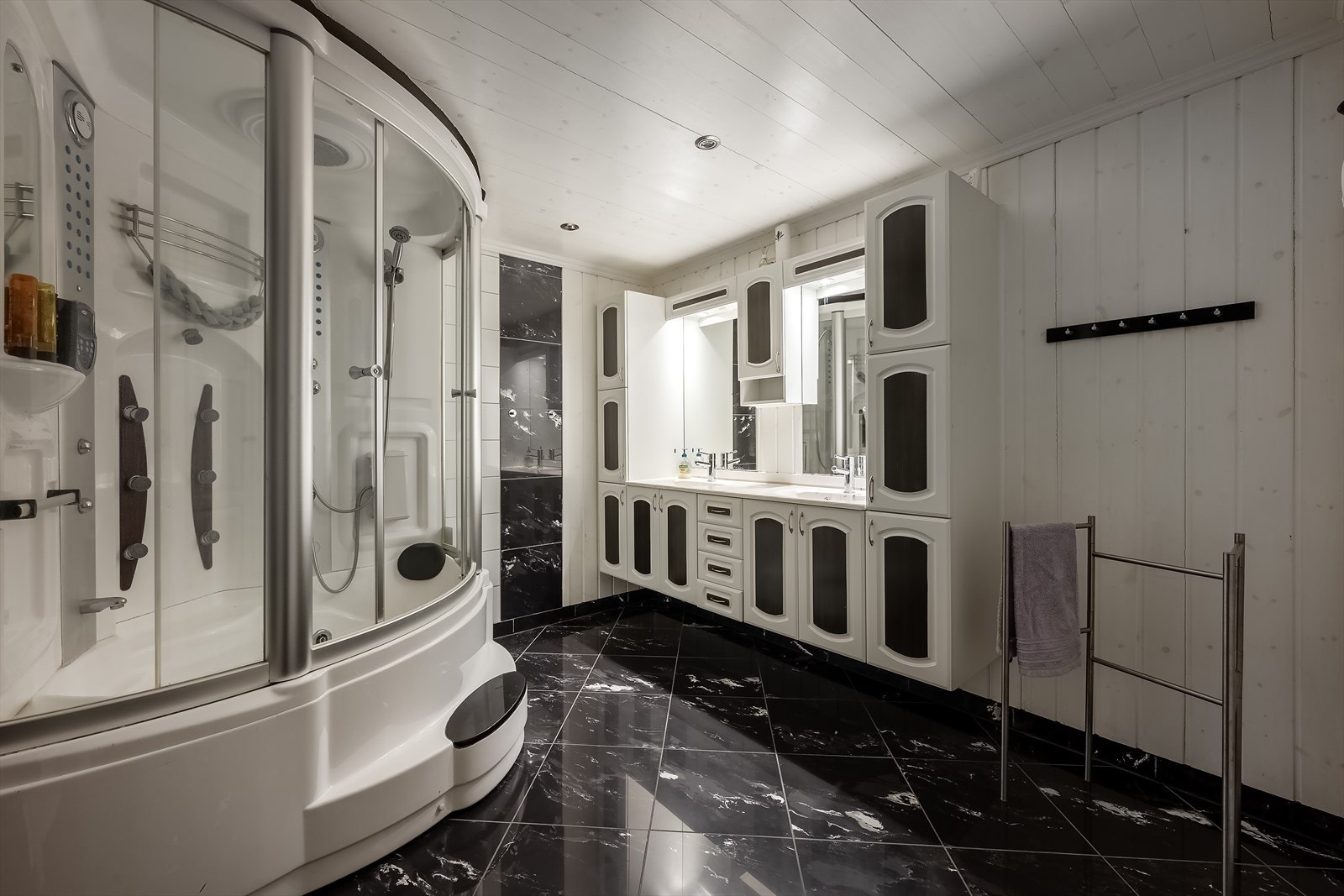 Det store badet har steamdusjkabinett med boblekar og baderomsinnredning ed dobbel servant og godt med skapplass Galleribilde