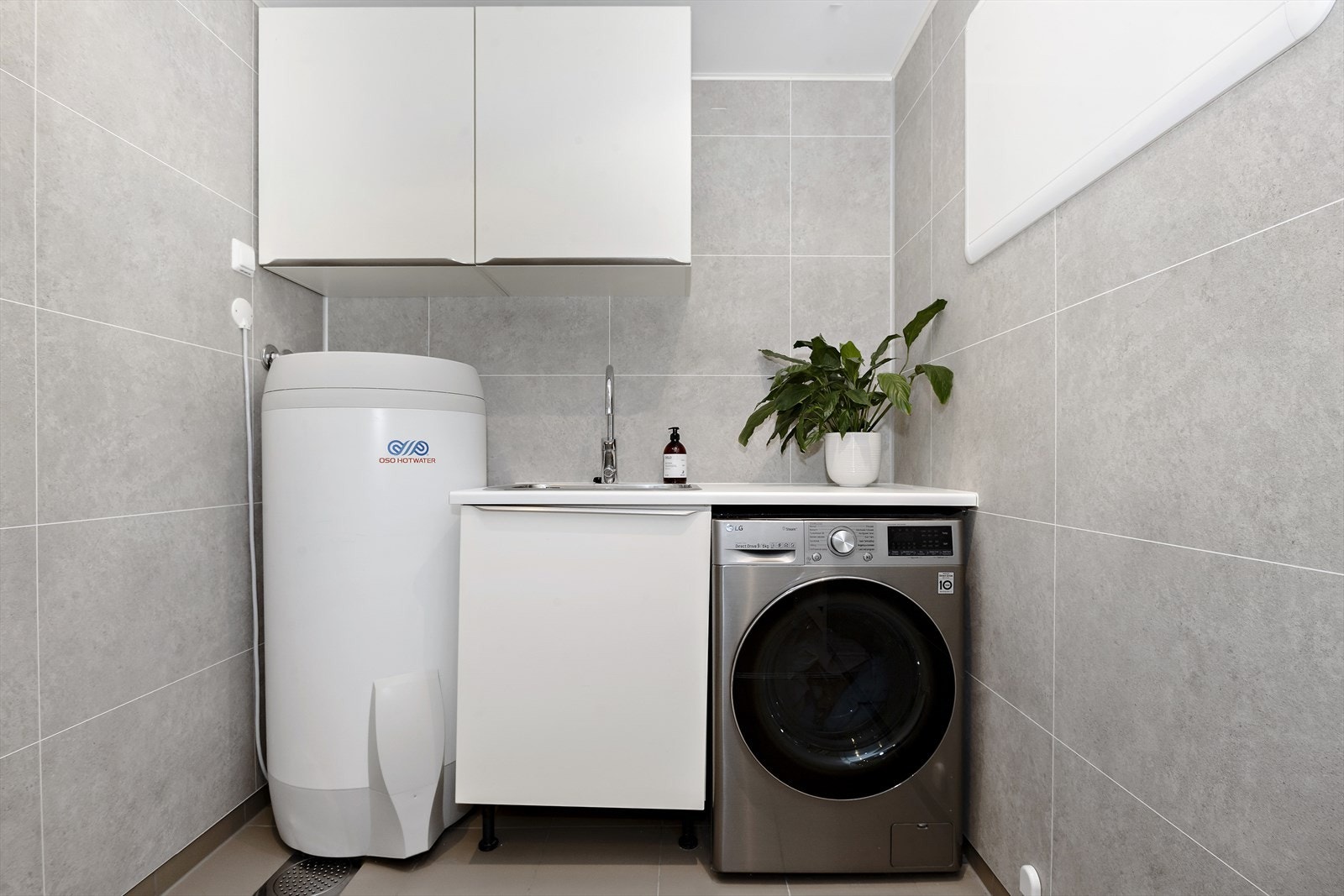 Bak takhøge skyvedører på badet, finn du ei romsleg vaskeromsavdeling. Galleribilde