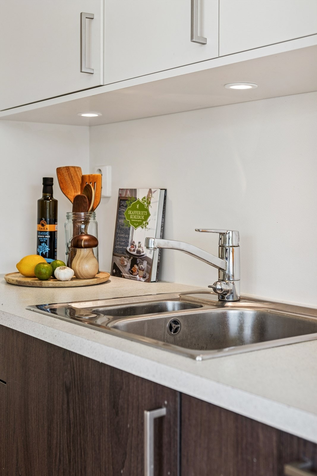 Det er nedfelt oppvaskkum med ett-greps armatur, benkebelysning og stikkontakter praktisk plassert over kjøkkenbenken. Galleribilde