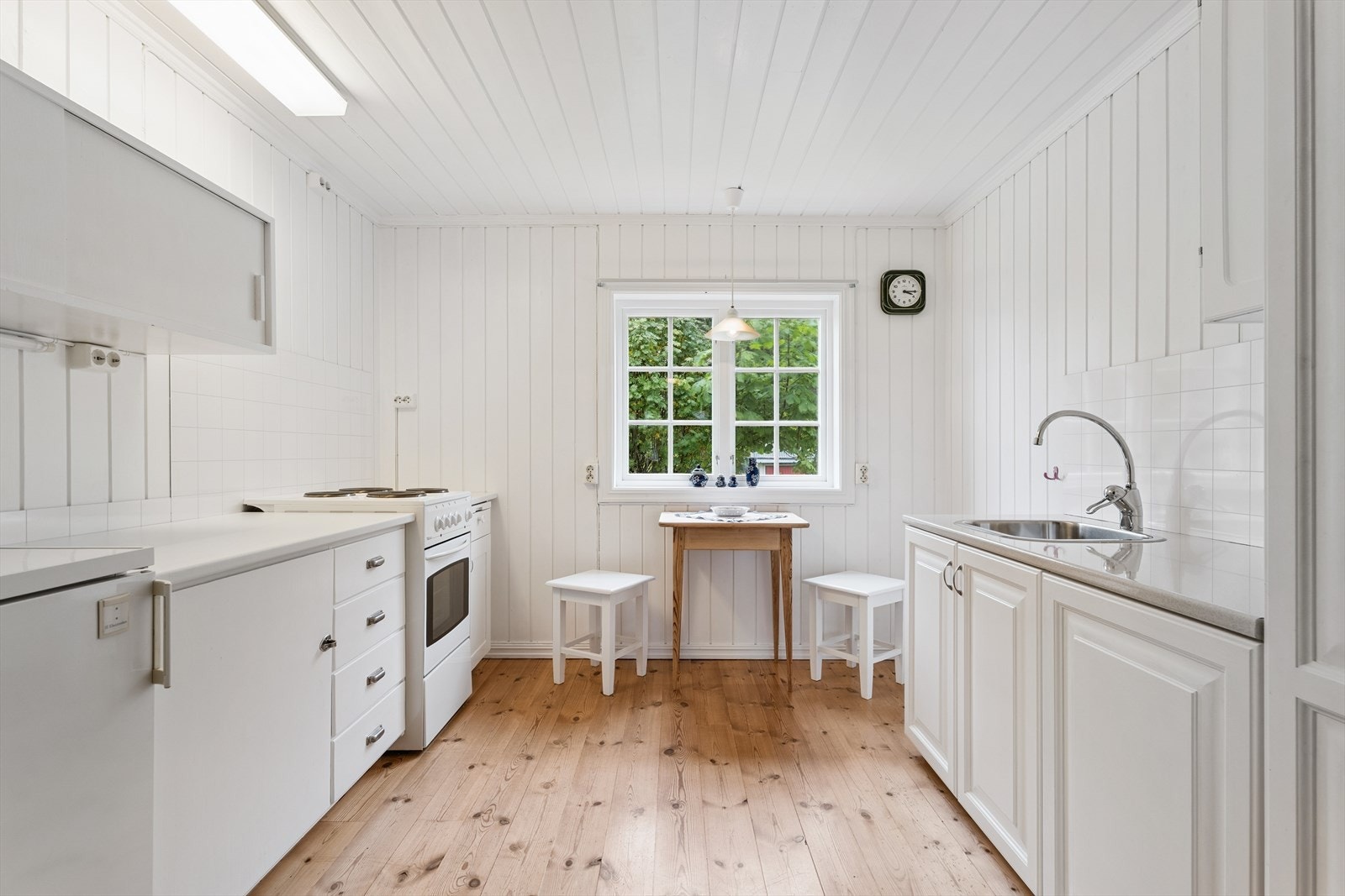 Lyst og funksjonelt kjøkken med plass til en liten spiseplass ved vinduet. Galleribilde