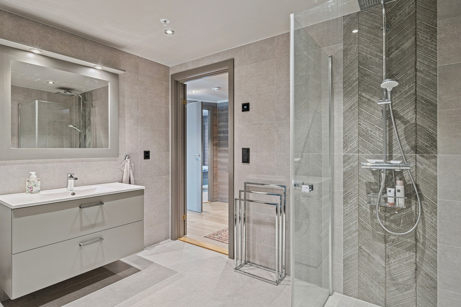 Bad 1 har tidsriktige fliser på gulv og vegg, og varme i gulv. Servantinnredning, toalett og dusjvegger i glass, samt opplegg for vaskemaskin. Galleribilde