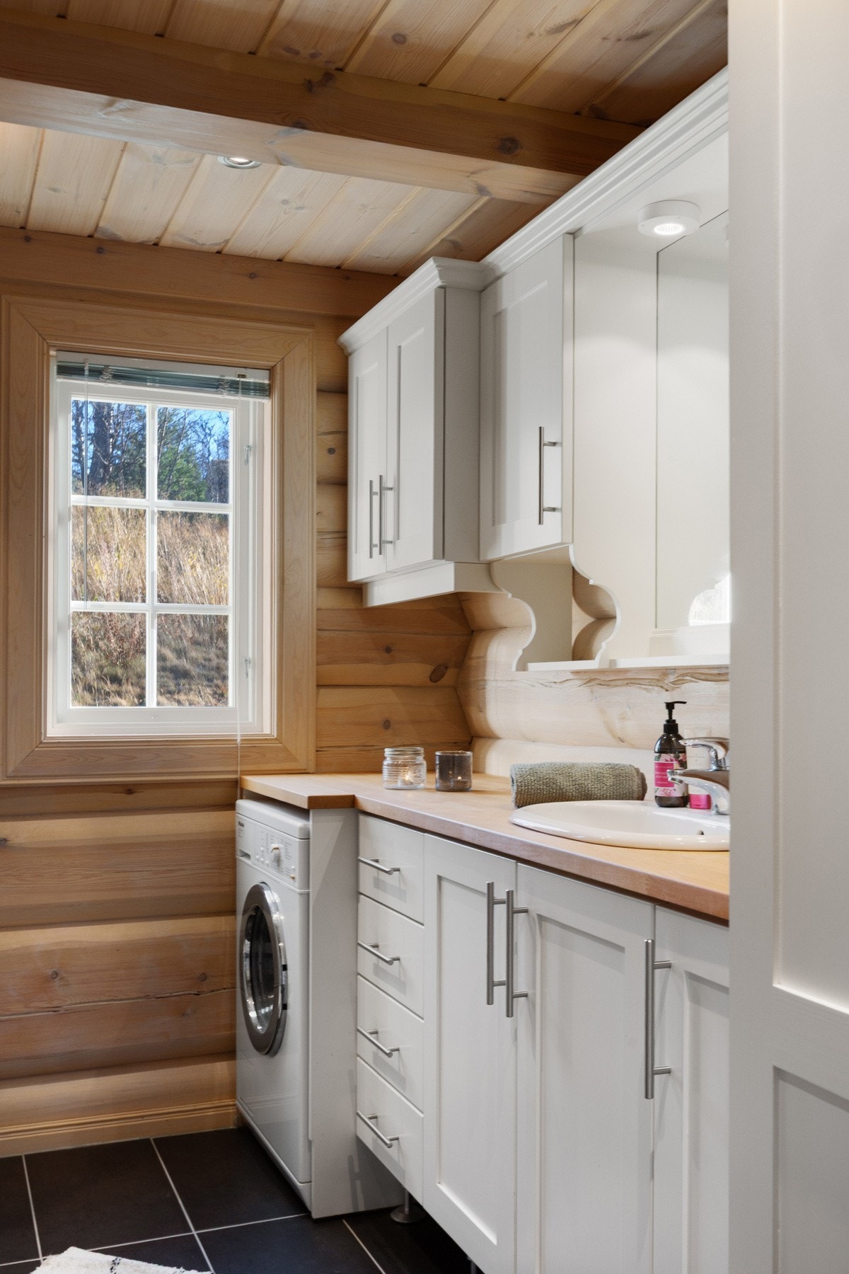 Baderomsinnredning i malt heltre med oppbevaringsplass i over- og underskap, med speil og tilhørende belysning. Galleribilde