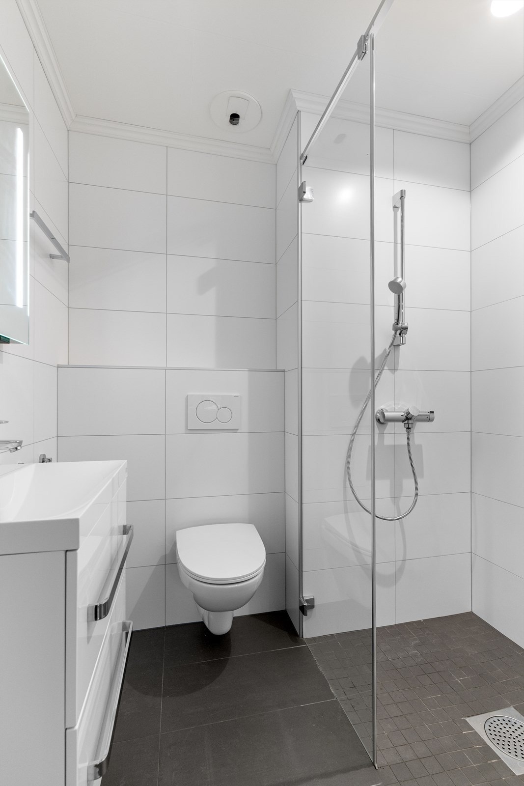 Flislagt bad med innredning, vegghengt toalett og dusjnisje. Galleribilde