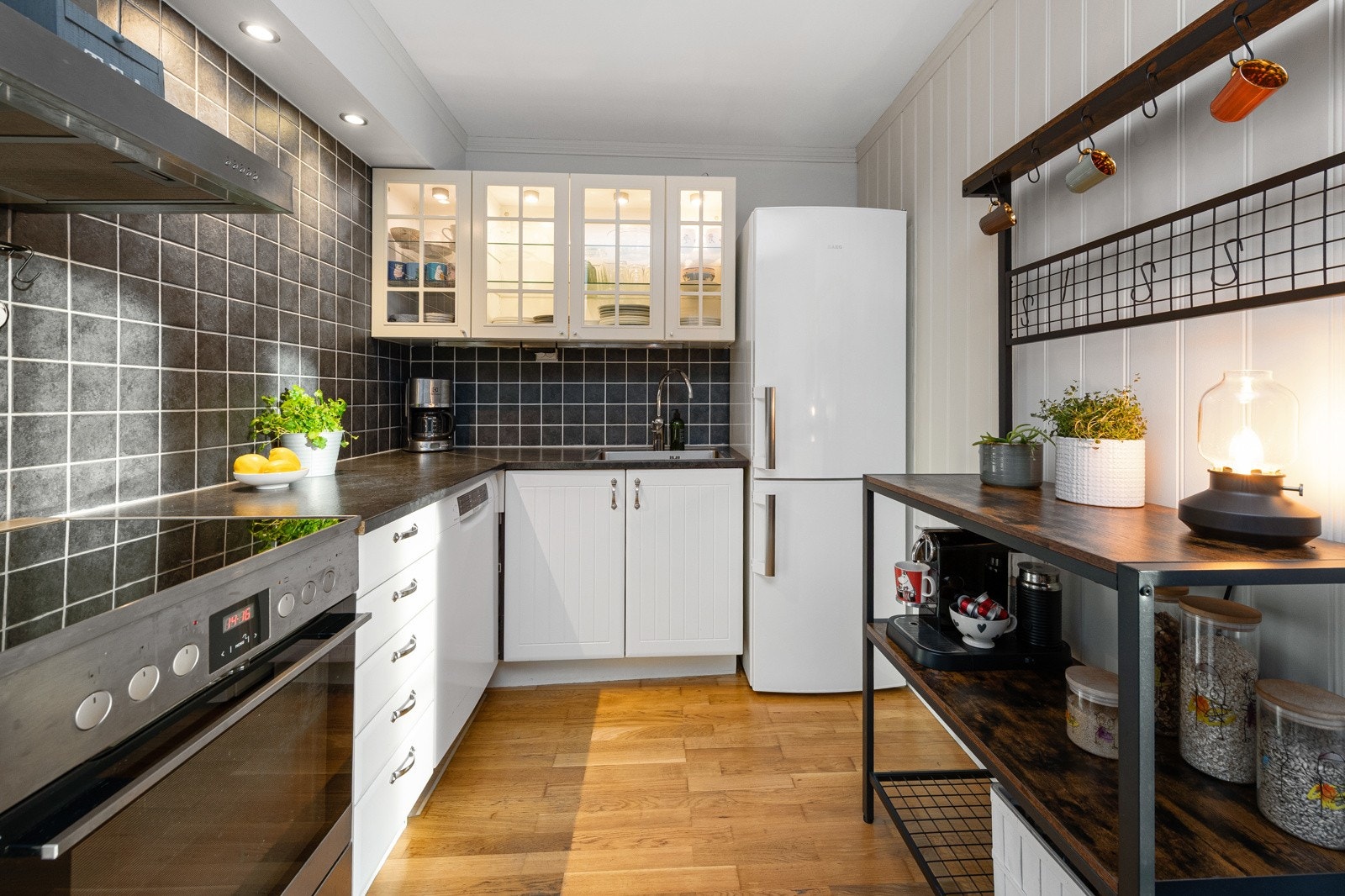 Koselig kjøkken med hvit kjøkkeninnredning. Vitrinedører på overskap. Lys i overskap skaper en koselig effekt Galleribilde