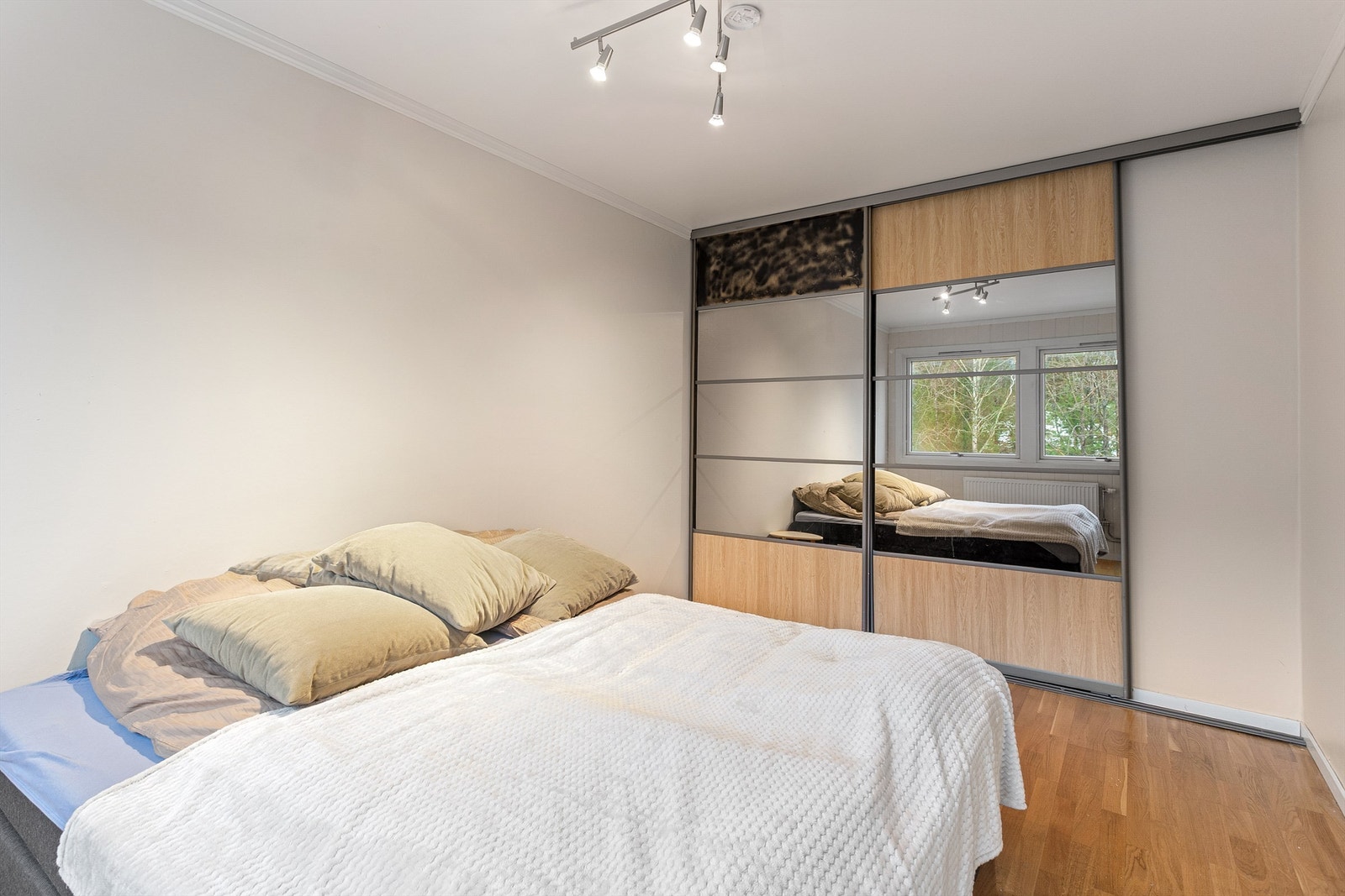 Rommet har en romslig skyvedørsgarderobe i glatt utførelse med speilfronter Galleribilde