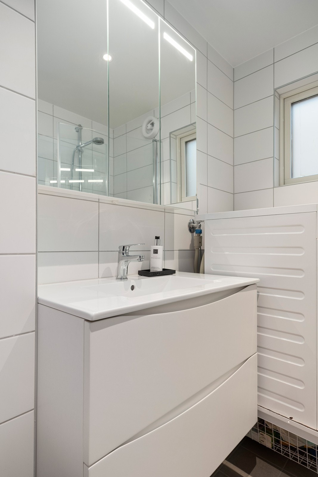 Baderomsinnredning med heldekkende servant og speilskap med integrert belysning. Galleribilde