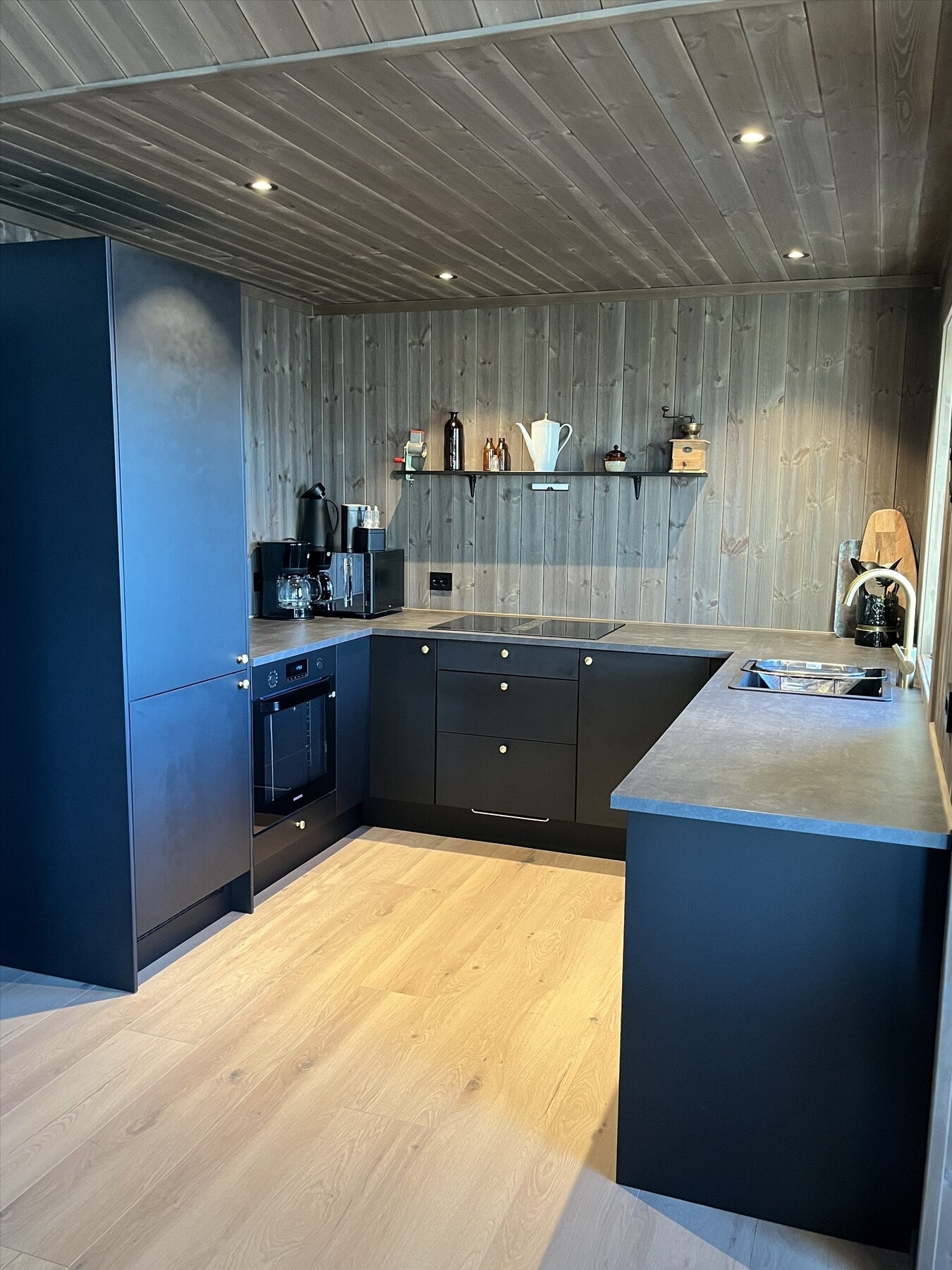 Moderne kjøkkeninnredning i mørk utførelse med laminat benkeplate. Løsningen uten overskap gir et luftig uttrykk. Galleribilde