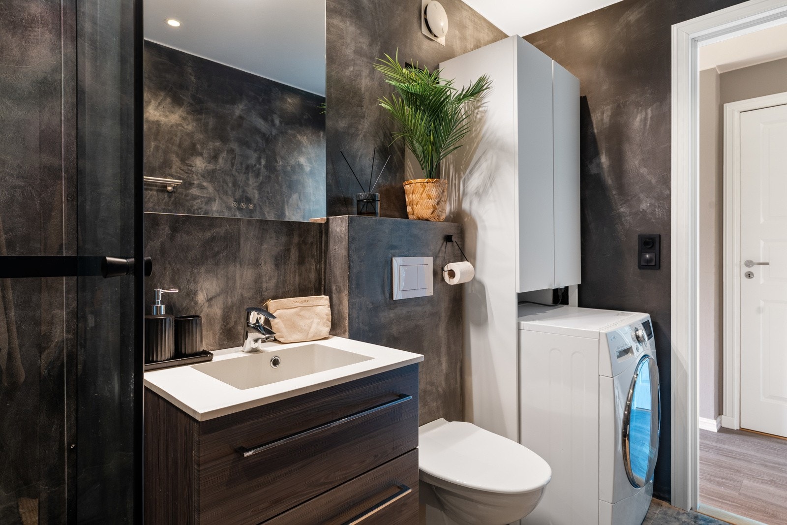 nnredning med servant, vegghengt toalett, dusjvegg i glass og dusjgarnityr og opplegg til vaskemaskin. Galleribilde