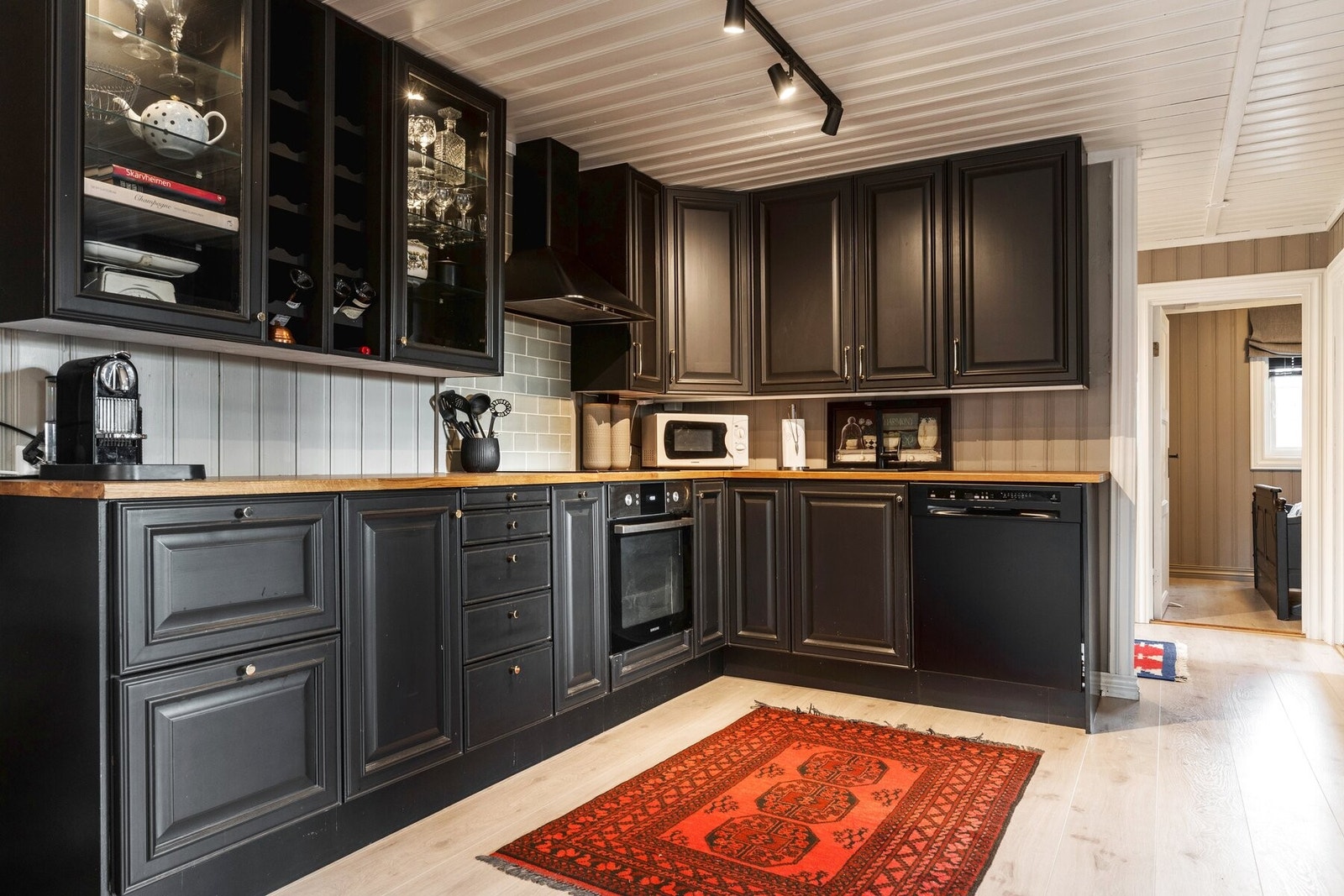 Kjøkkeninnredning med profilerte lakkerte fronter i en moderne sort farge. Det er god oppbevaringsplass i skuffer og skap. Galleribilde