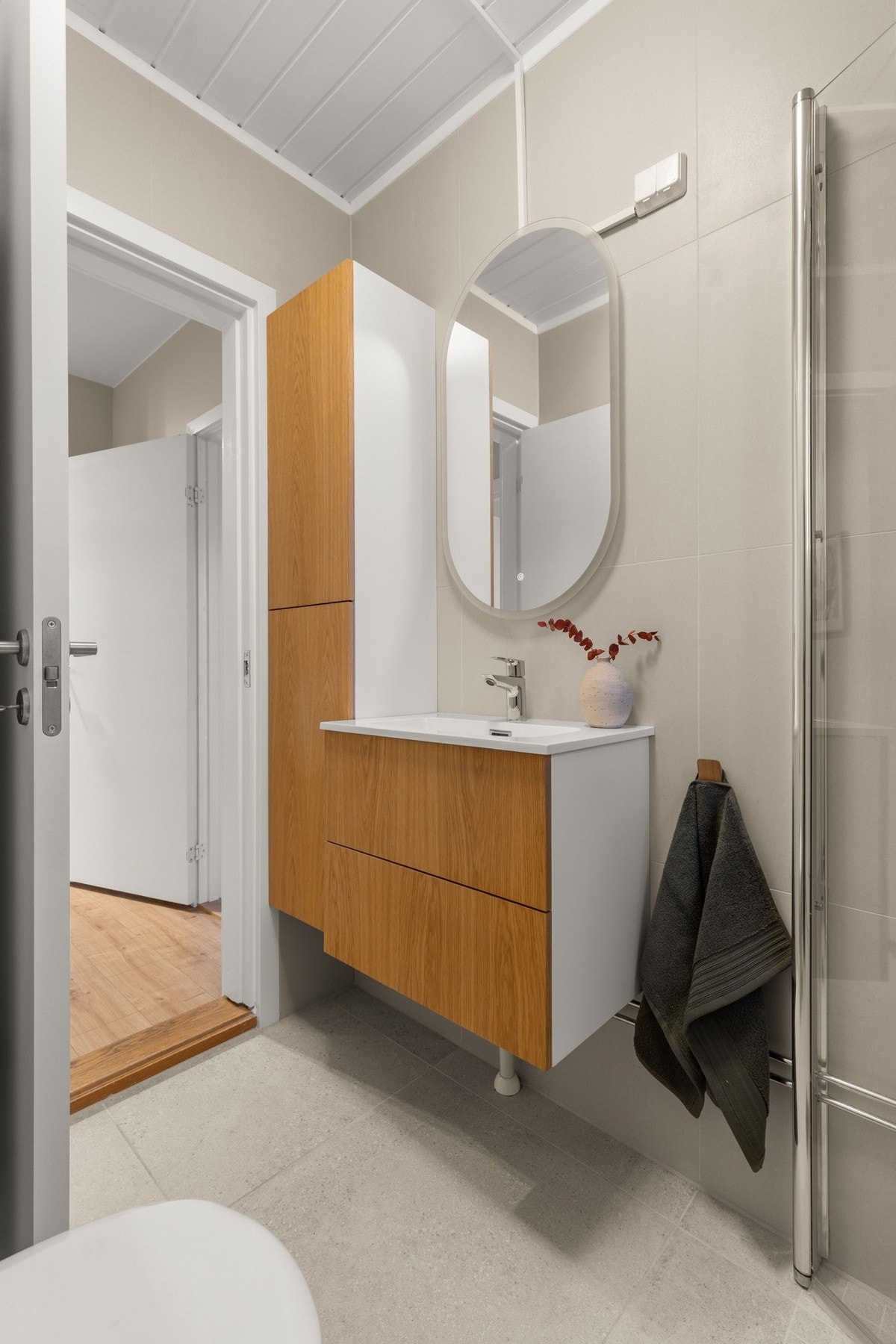 Badet er innredet med dusjhjørne, servant i praktisk innredning og toalett, alt gjennomført med stilrene detaljer. Galleribilde