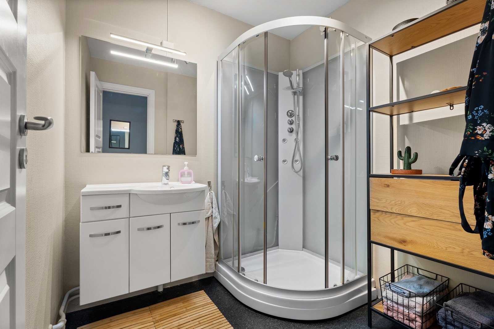 Badet har et romslig dusjkabinett og servantinnredning med lyssatt speil over. Galleribilde