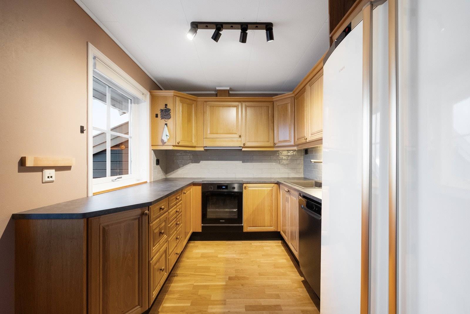 Kjøkkenet er i eget rom, og har parkettgulv og kjøkkeninnredning med integrerte hvitevarer og profilerte fronter. Galleribilde