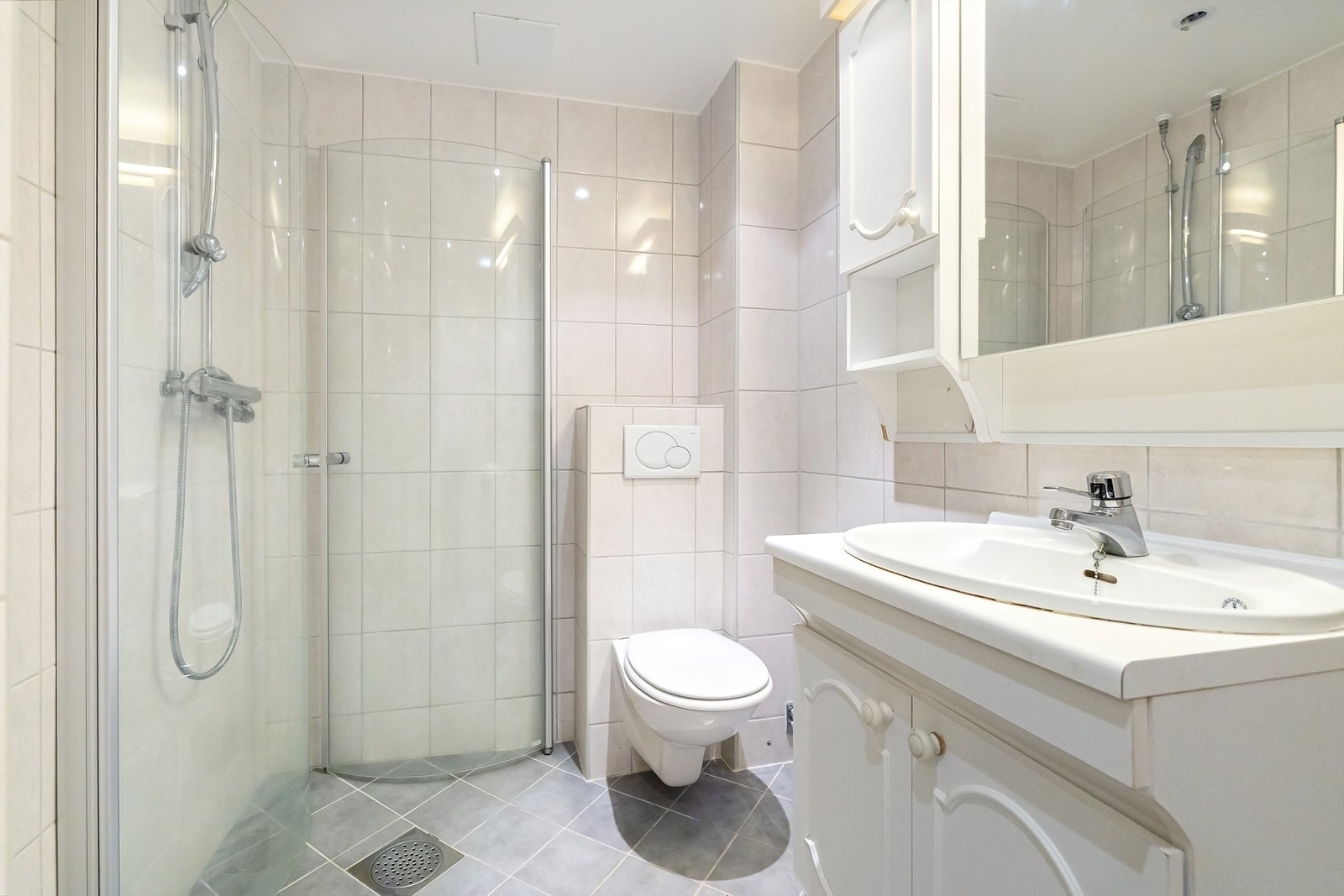 Flislagt gulv med varme og flislagte vegger. Servantinnredning med profilerte fronter og benkeplate av laminat. Speilskap over servant med overlys og stikkontakt. Galleribilde