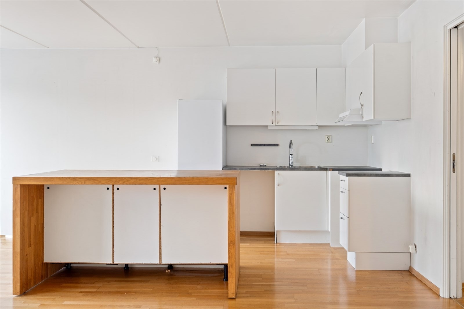 Eldre kjøkken med behov for oppgradering - god plass til barstoler og sosiale løsninger. Galleribilde