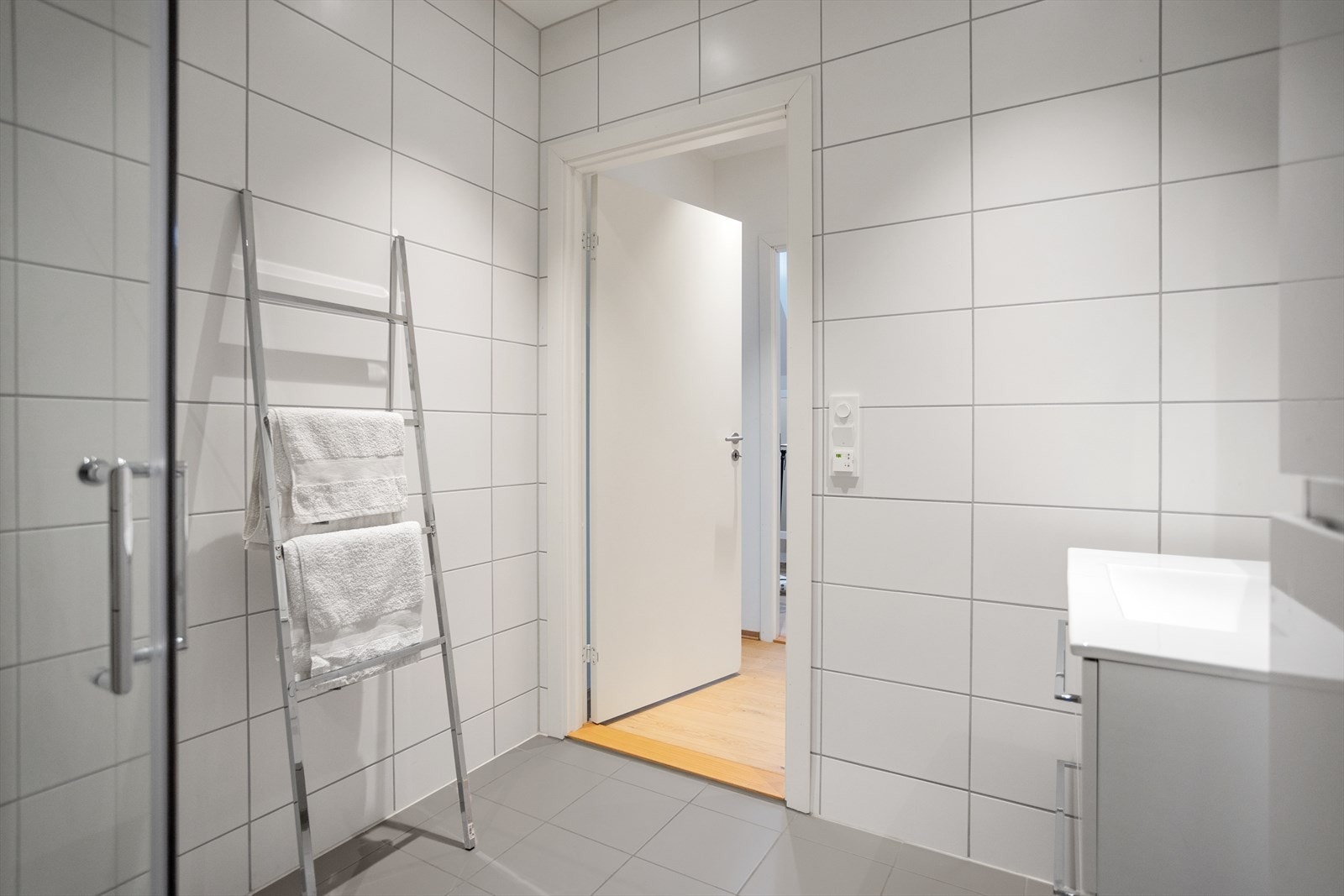 Badet er innredet med veggmontert toalett og dusjvegger/hjørne samt innredning med nedfelt servant Galleribilde