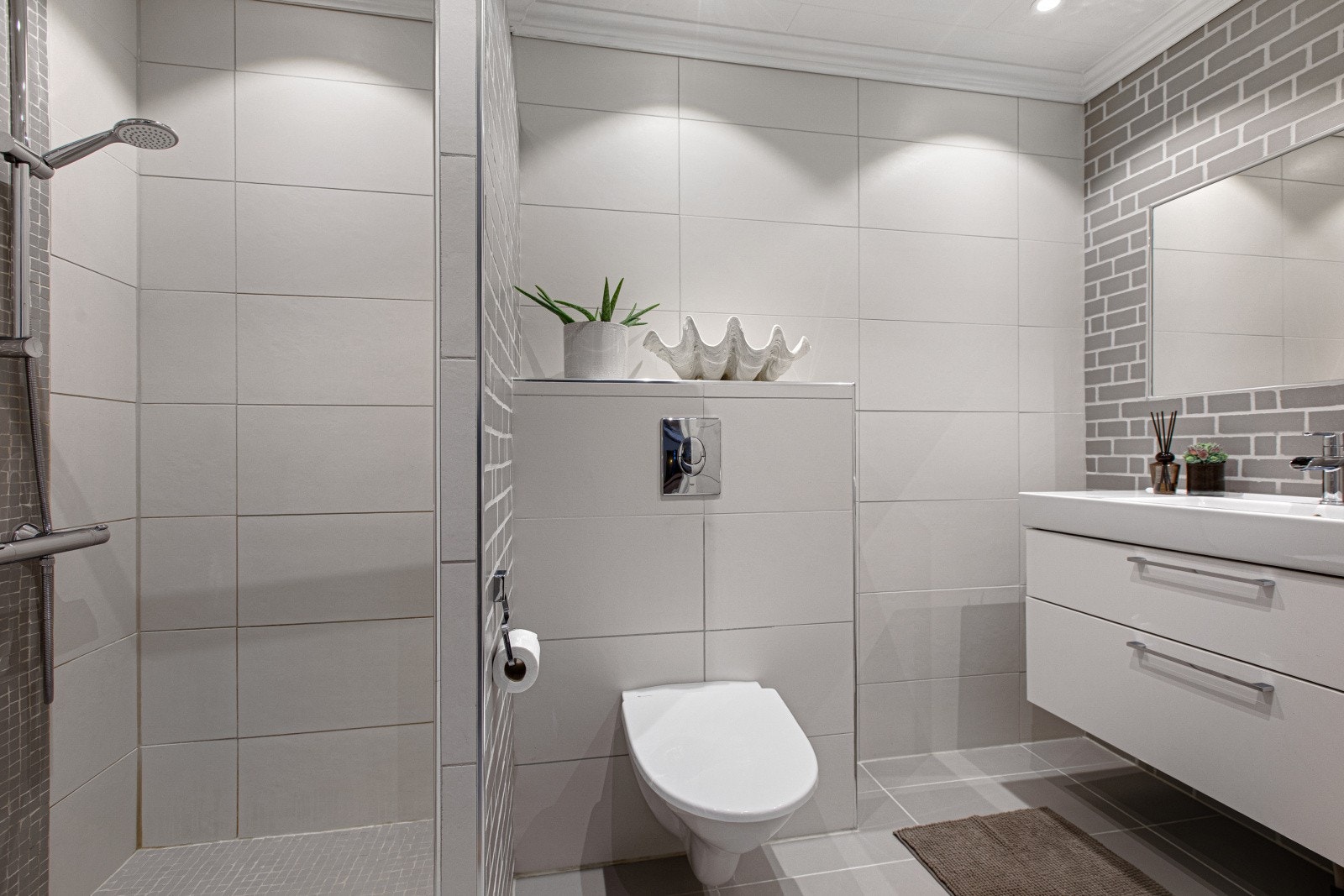 Badet i første etasje er delikat og ble oppgradert i 2012. Rommet er innredet med dusjnisje, vegghengt toalett og servantinnredning med tilhørende speil. Galleribilde