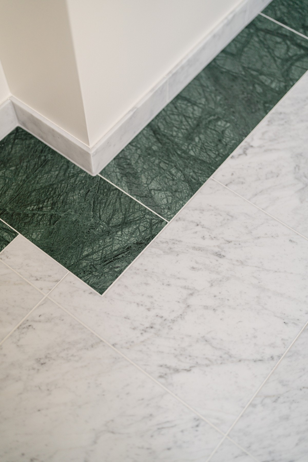 Det er lagt bord rundt flisene på baderom i grønn marmor som matcher servant. Lister på badet i carrera-marmor. Galleribilde