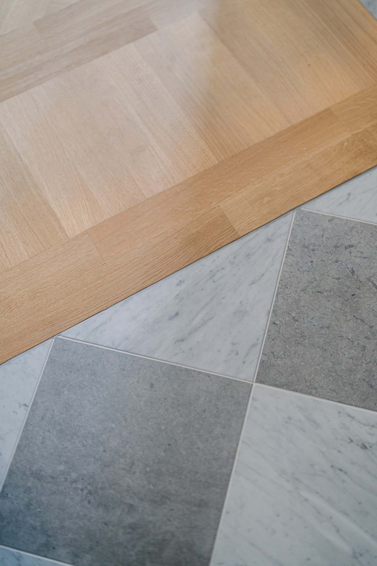 Italiensk Carrera-marmor flis og kalkstein i eksklusivt mønster. Terskelfri overgang til hellimt fiskebensparkett. Galleribilde