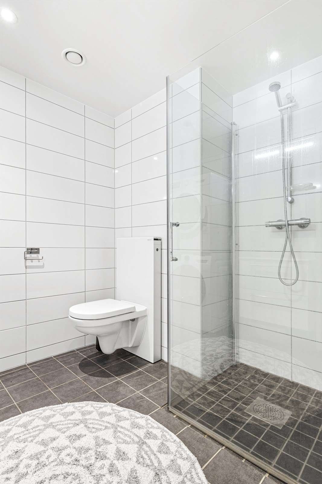 Badet har dusjhjørne med foldedører av glass Galleribilde