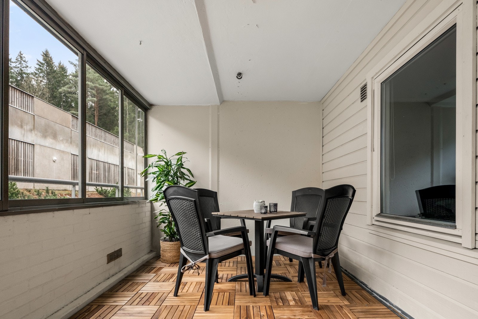 Balkongen har treheller på gulvet, lysmalte vegger og tett rekkverk toppet med skyvbare glass. Galleribilde