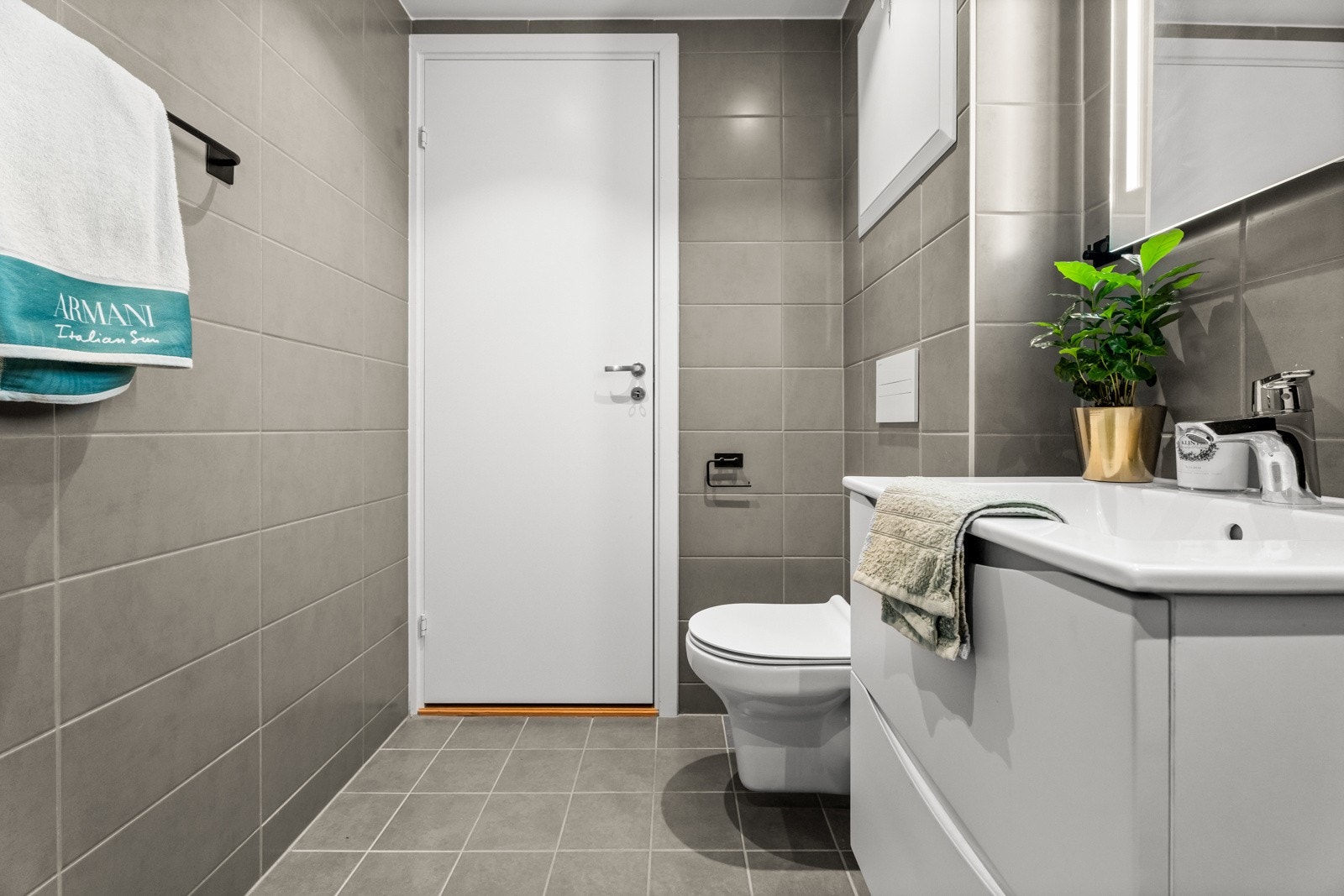 Baderomsinnredningen består av vegghengt skuffeseksjon med hvite, slette fronter, heldekkende servant og et speil med integrert belysning. Galleribilde