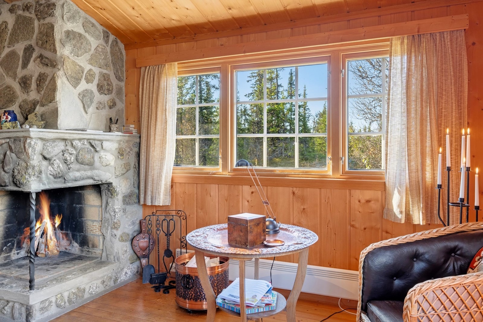 Den klassiske hyttestilen med ubehandlet trepanel på vegger og vedfyring skaper en varm og stemningsfull atmosfære som setter hyttekos i fokus. Galleribilde