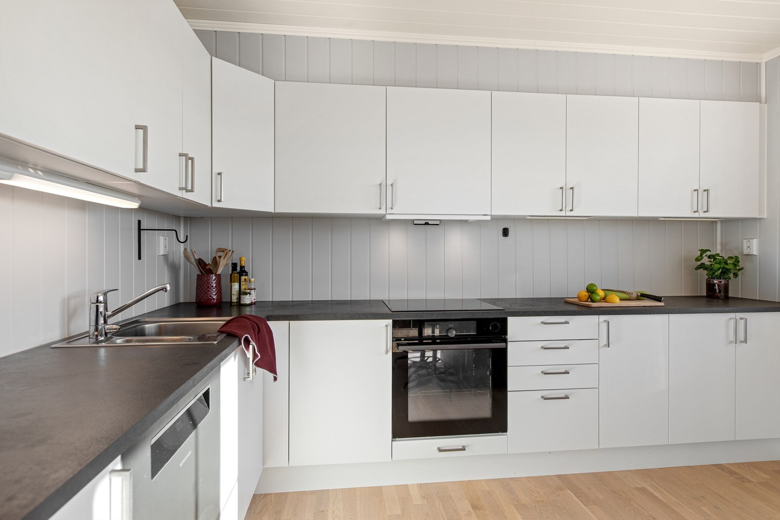 Kjøkkeninnredning har hvite glatte fronter og laminert benkeplate Galleribilde