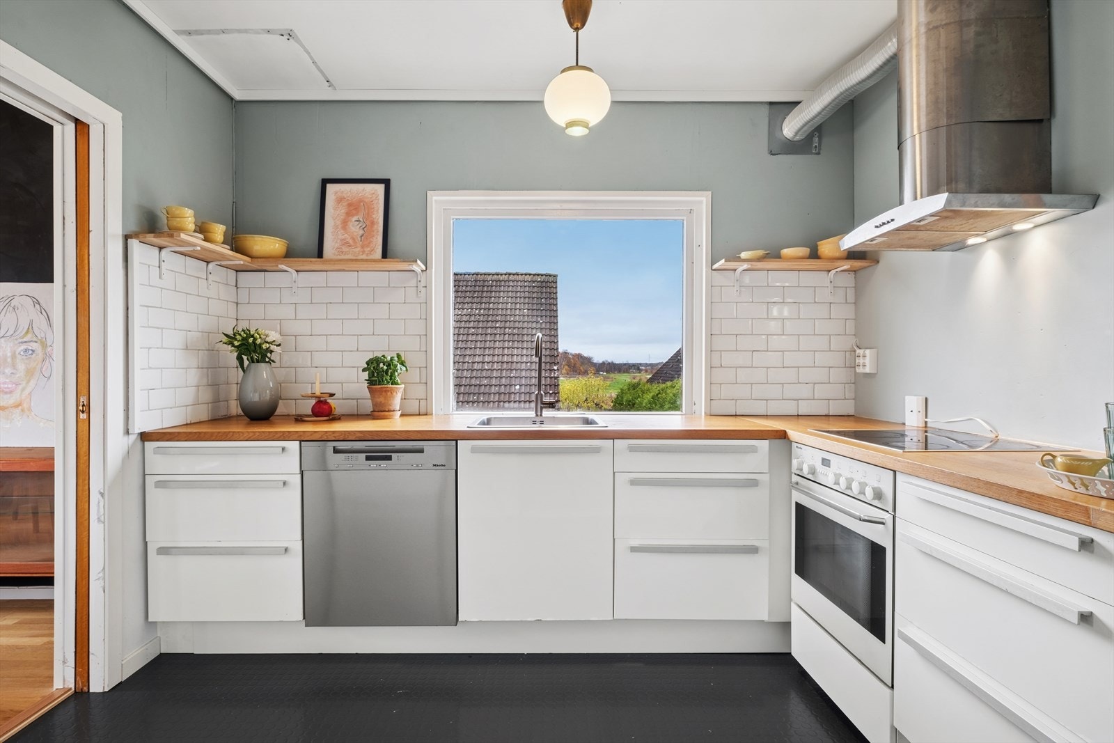 Kjøkkeninnredning med samme stilrene uttrykk - lyse slette fronter, heltre benkeplate og oppvaskkum. Galleribilde