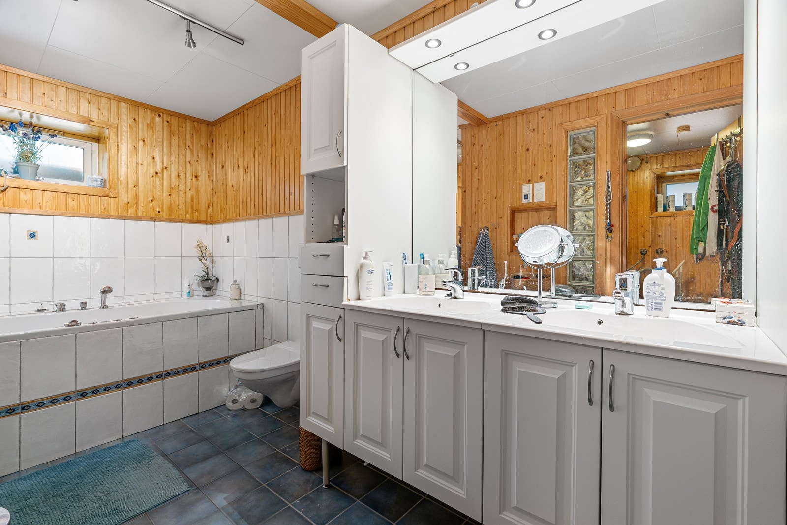 Romslig bad med badekar, dobbelservant og vegghengt toalett.