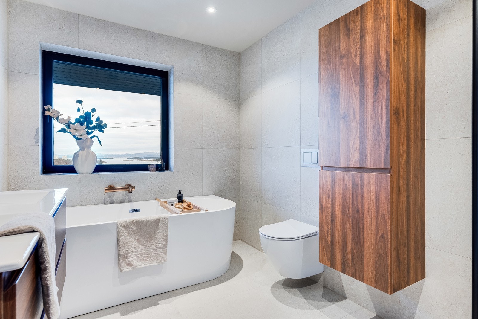 Badet er innredet med badekar, seksjon med dobbelservant, vegghengt toalett og dusjhjørne med glassvegger. Galleribilde