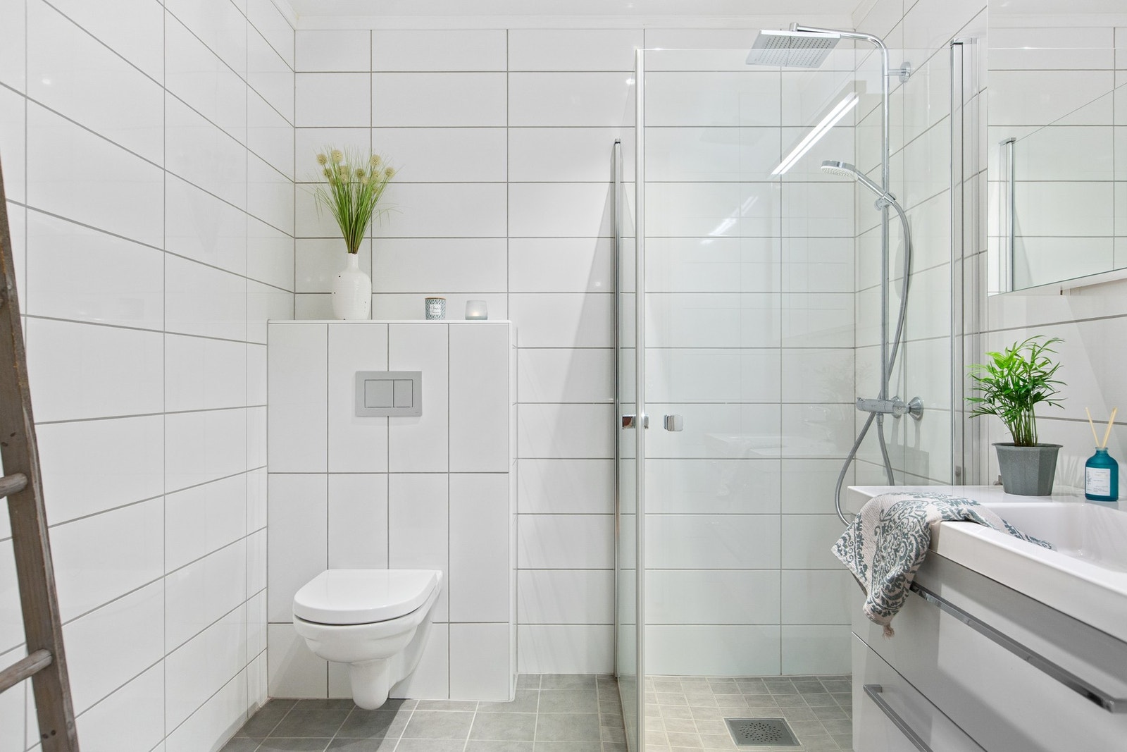 Lyse og innbydende baderom, med veggehengt toalett, dusj med glassdører og baderomsinnredning med servant, skuffer og speilskap. Galleribilde