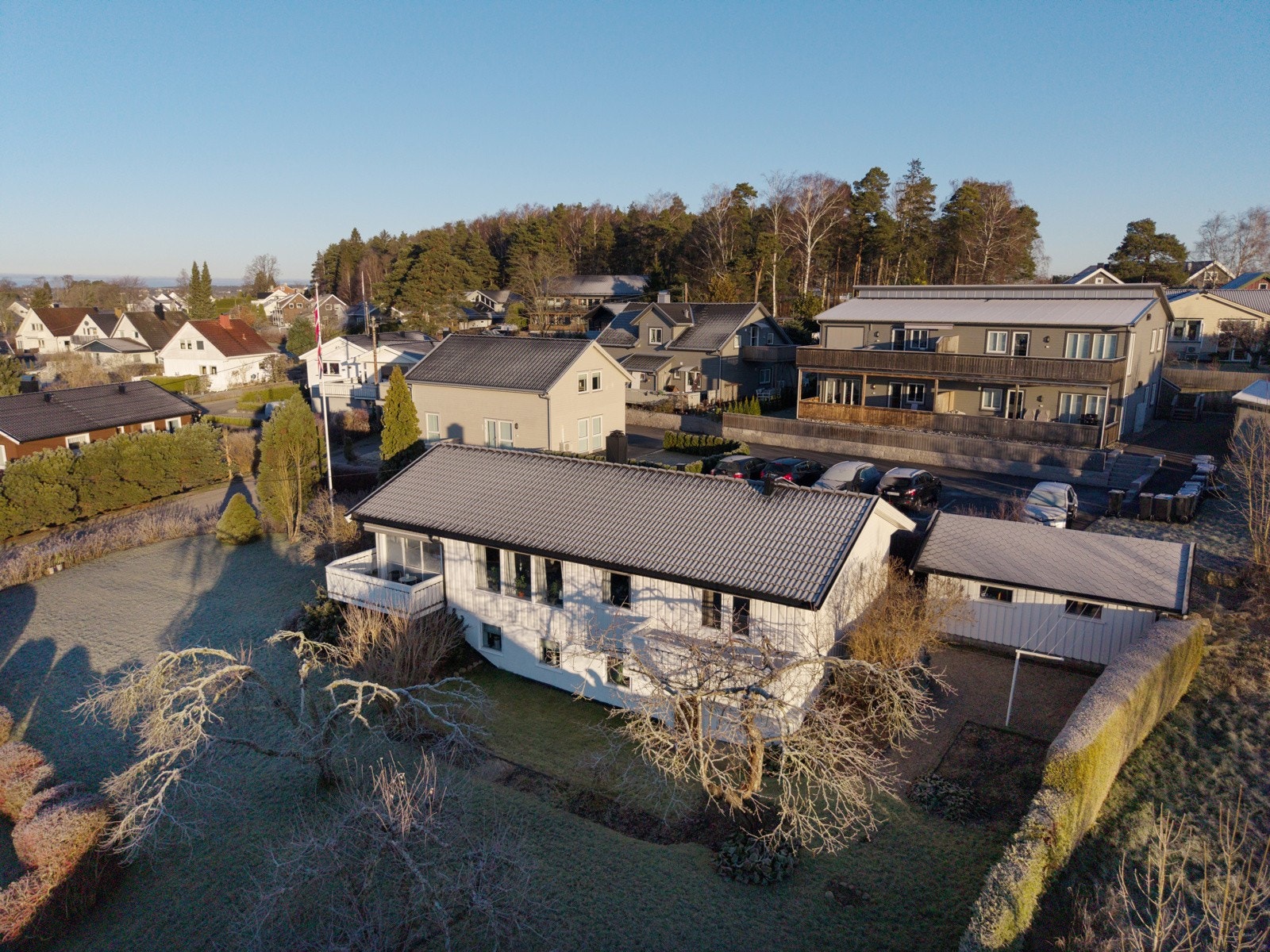Dronefoto viser hus og garasje med hagen som rammer inn eiendommen på en fin måte. Galleribilde