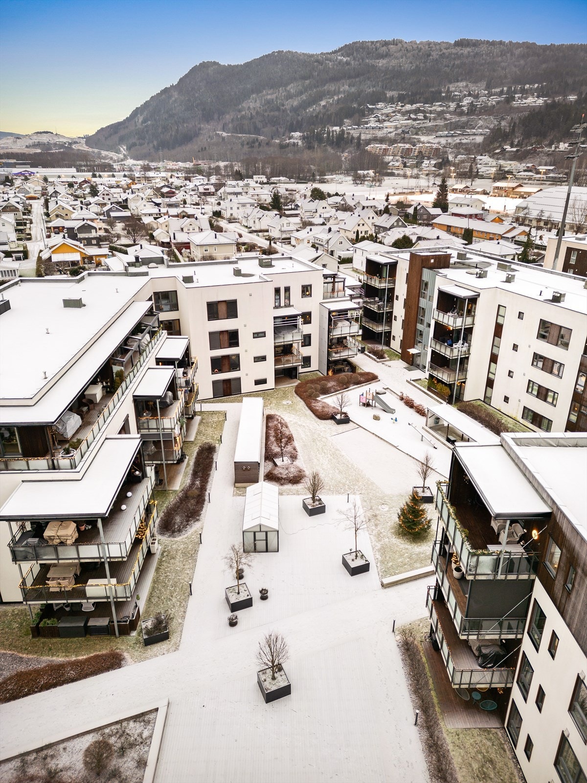 Opparbeidet utvendige fellesarealer med gressplen, pen beplantning, lekeplasser, sitteplasser samt veksthus/drivhus Galleribilde