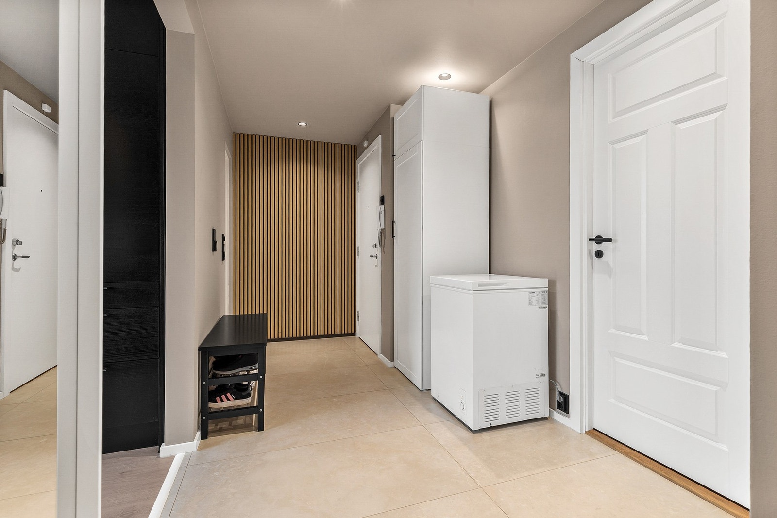 Romslig entré med flislagt gulv, dørcalling og plass til garderobeskap for oppbevaring av yttertøy og sko Galleribilde