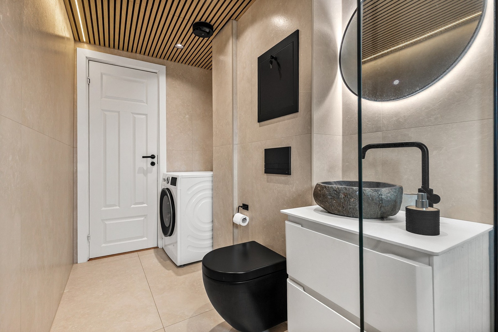 Badet er innredet med dusjhjørne med glassvegg, vegghengt toalett, baderomsinnredning med bollevask og opplegg for vaskemaskin Galleribilde