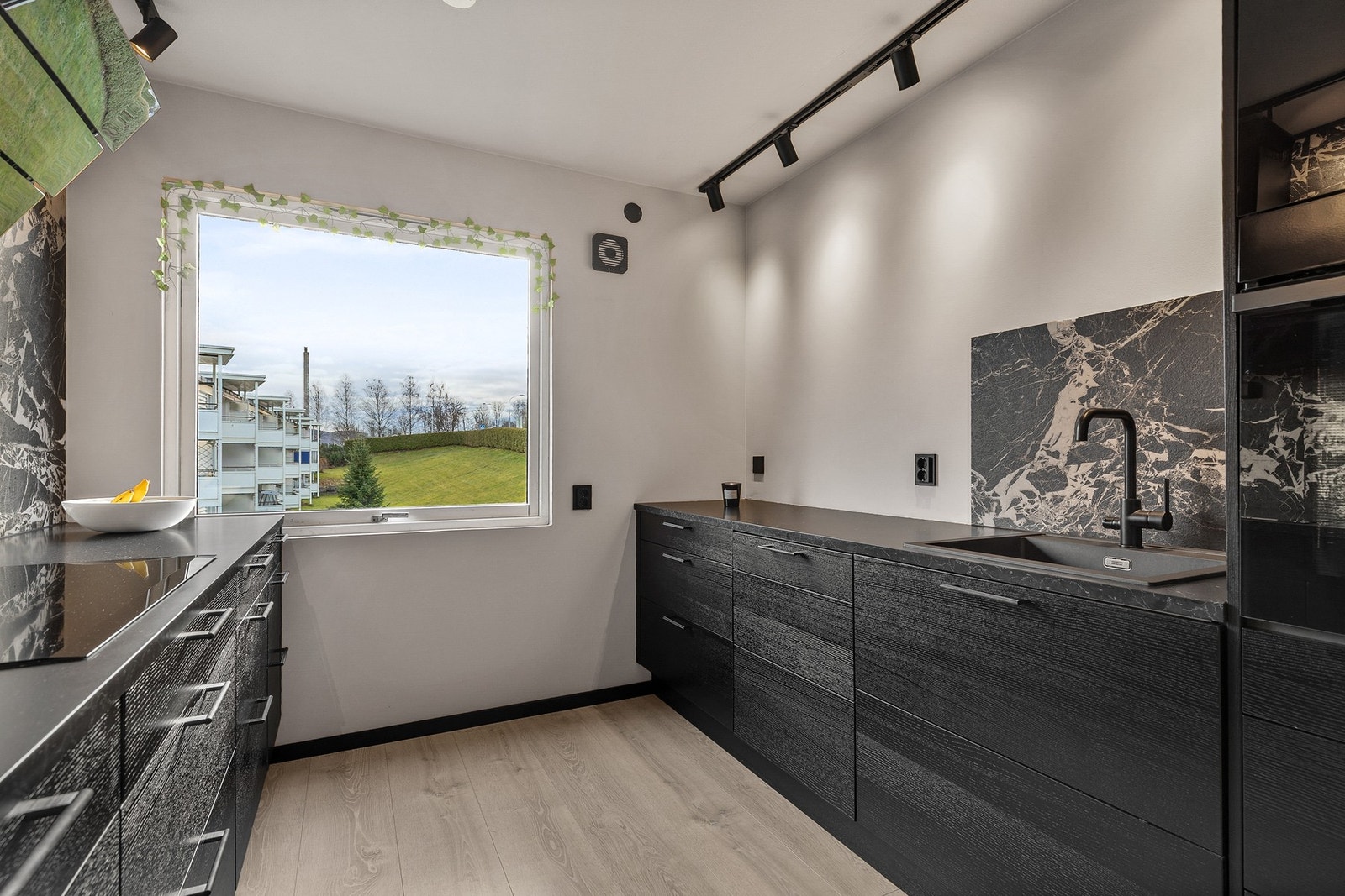 Innredningen har integrerte hvitevarer, herunder kjøl/fryseskap, oppvaskmaskin, induksjonstopp, kombiovn og stekeovn Galleribilde