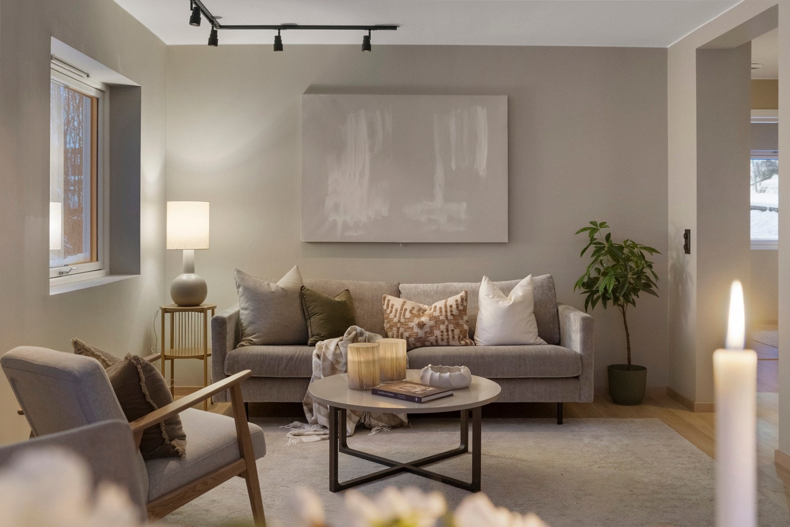 Videre åpner boligen seg mot en romslig og innbydende stue med malte overflater i duse beige toner. Galleribilde