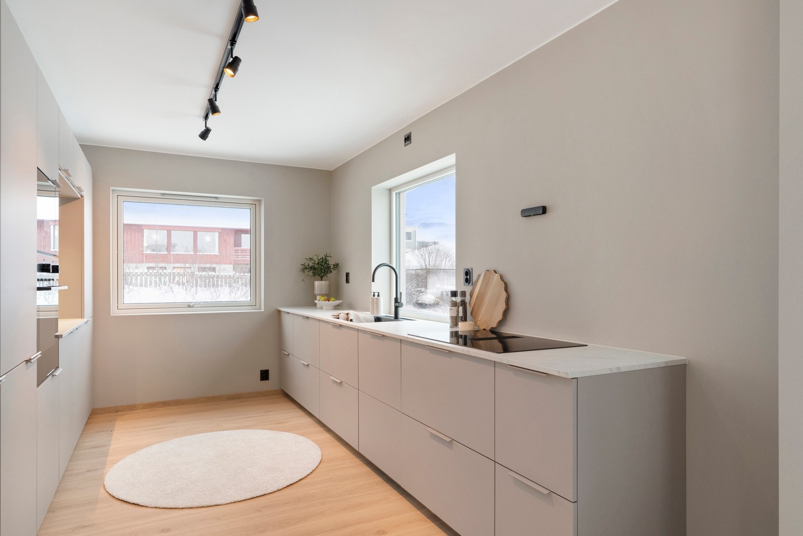 Stuen glir sømløst over i et svært romslig kjøkken fra Kvik, levert i delikate beige/grå fronter med hvit benkeplate. Galleribilde