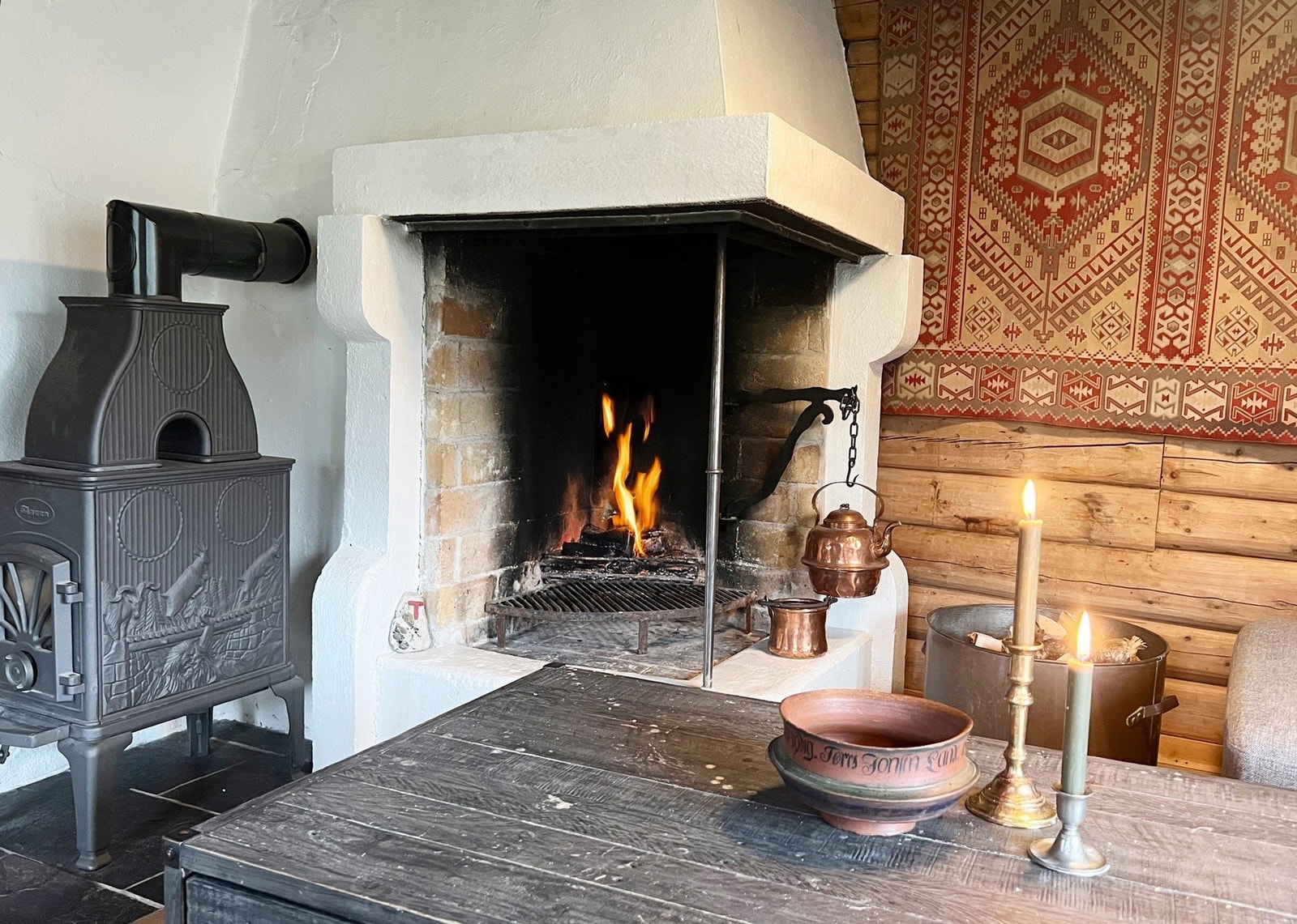 Praktisk løsning med effektiv vedovn ved siden av koselig, åpen peis. Galleribilde