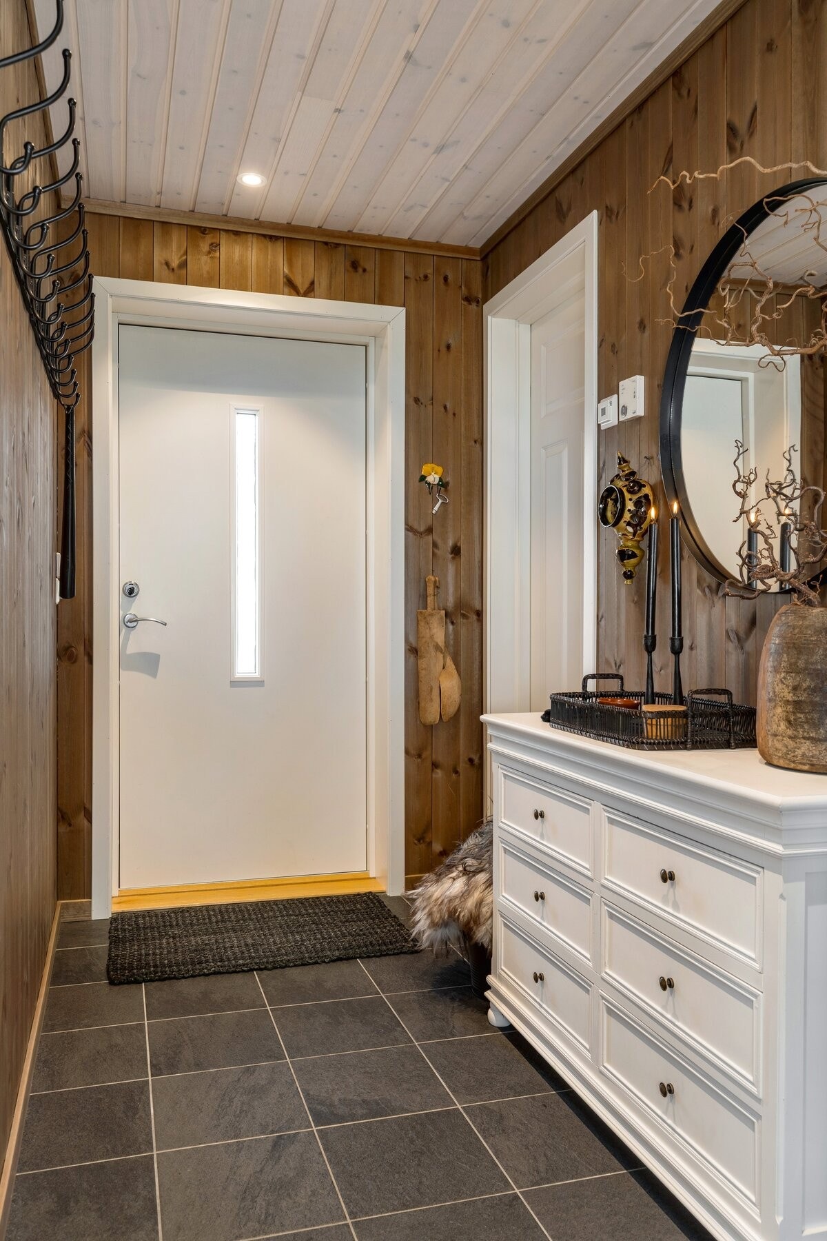 Velkommen inn i flislagt entré med inngang til praktisk bod/teknisk rom. Galleribilde