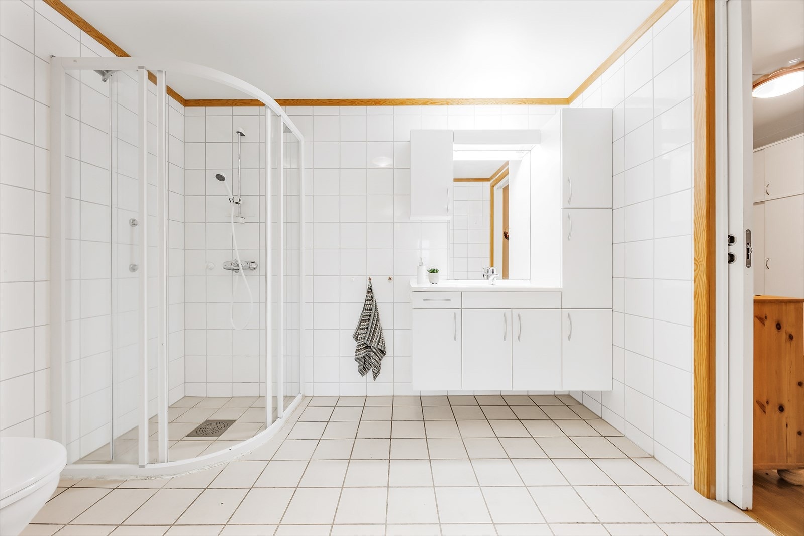 Innredningen har servant over skapmøblement, matchende høy- og veggskap, samt speil med belysning i overkant. Galleribilde