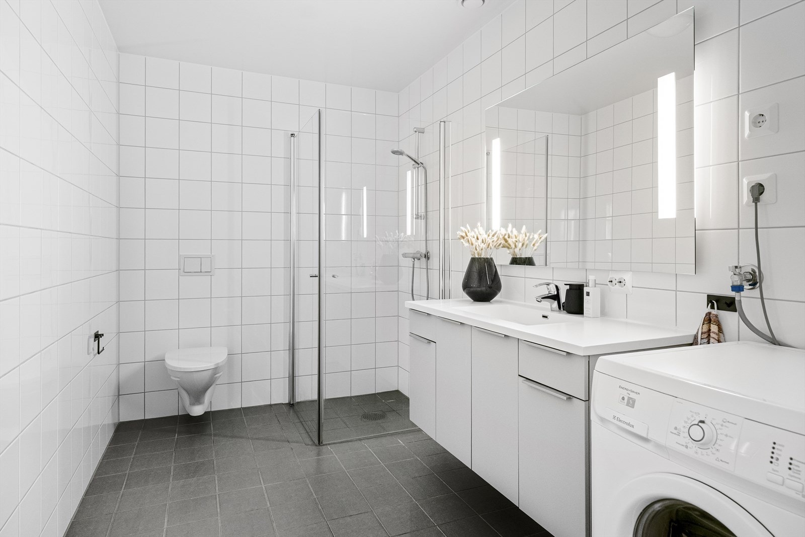 - Badet er helfliset med stort dusjhjørne med innfellbare dører og vegghengt servant - Galleribilde