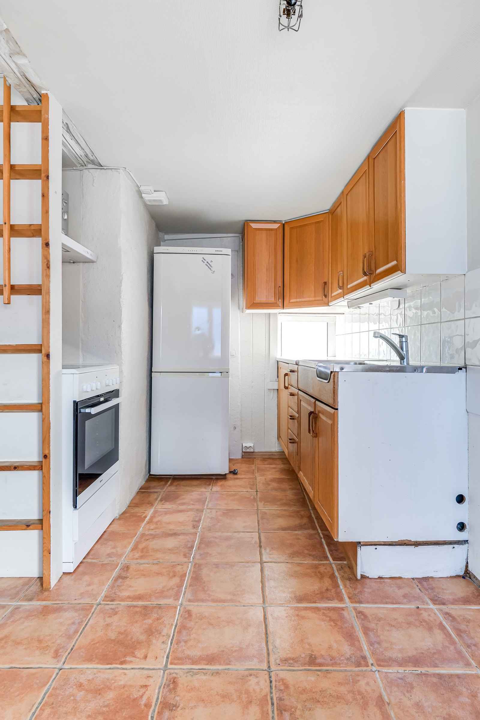 Det er profilerte fronter av eik, laminat benkeplate og rustfritt benkebeslag med integrert oppvaskkum og utslagsvask samt ettgreps kjøkkenbatteri. Galleribilde