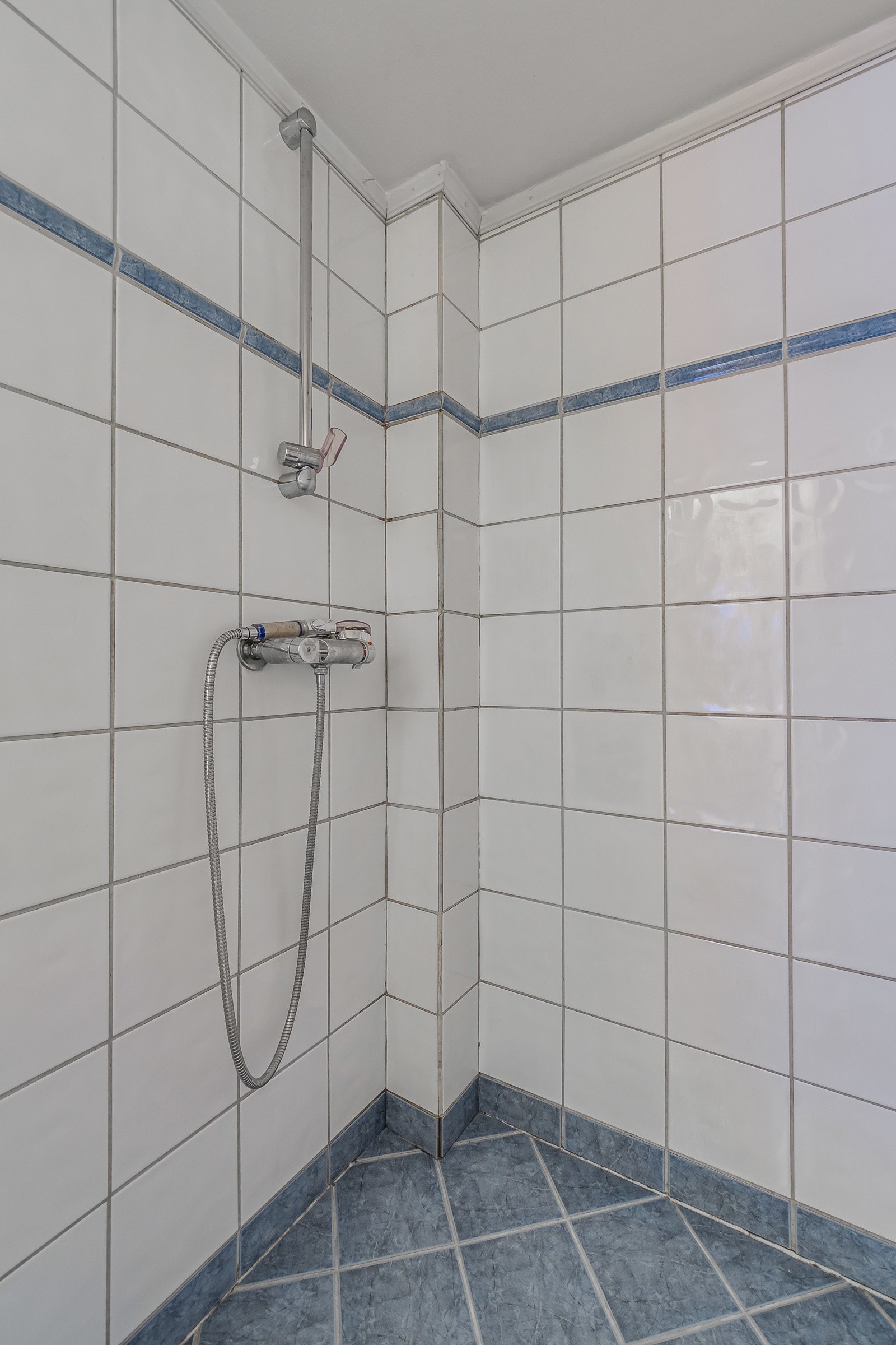 Baderommet har porselensservant, veggmontert speilskap med overliggende lyslist, gulvstående toalett (2023) og dusjhjørne. Det er også opplegg for vaskemaskin. Galleribilde