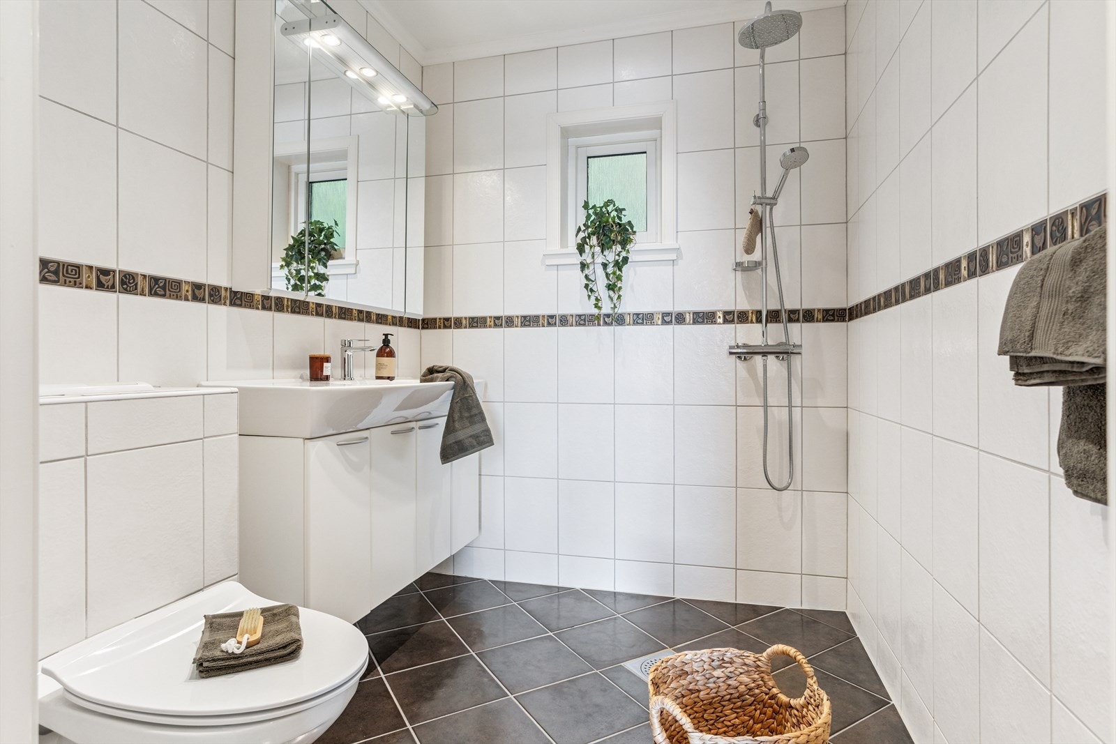 Badet er også flislagt, og inneholder vegghengt toalett, håndvask med skap, samt dusjsone. Galleribilde