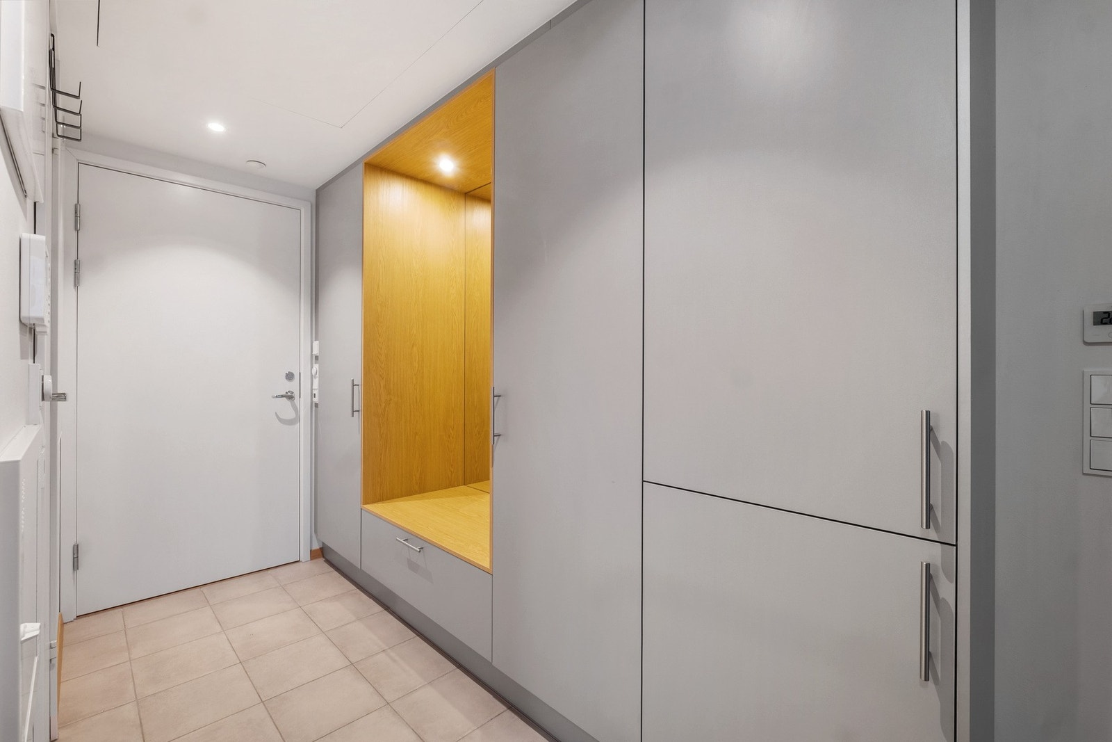 Moderen og innbydende entre med fliser på gulvet og en innebygd garderobeløsning. Galleribilde