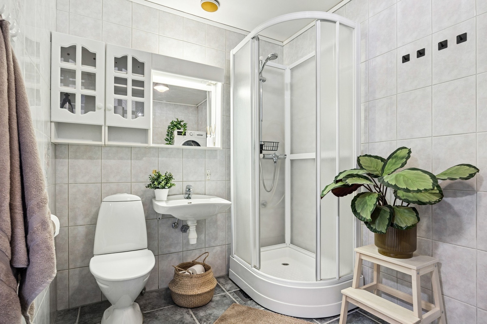 Badet er utstyrt med dusjkabinett, gulvstående toalett, vegghengt servant med skap, speil med overlys samt opplegg for vaskemaskin. Galleribilde